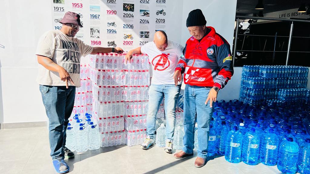 Alpha Team members standing beside a large stack of branded bottled water